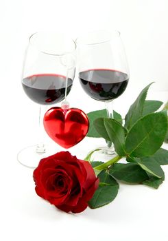 Two wineglasses with red wine, heart and red rose