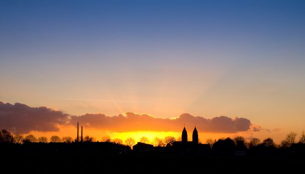 nice sunset with a silhouette of a village with church towers 
