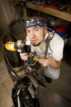 Hispanic mechanic working on a chopper style motorcycle