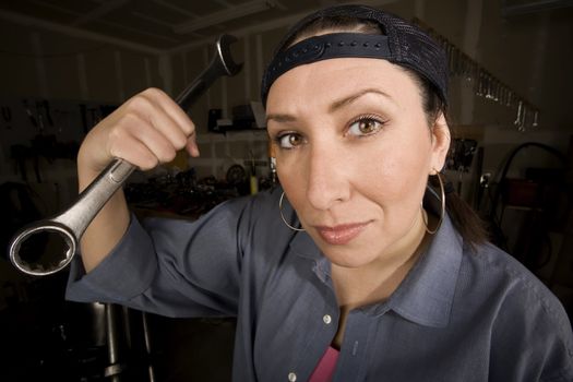Hispanic woman in a garage with wrench