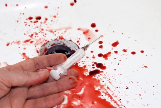human hand with a serynge  and  blood in a bathroom: suicide in a tub