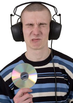 The young guy with ear-phones on a head and compact disk in hand