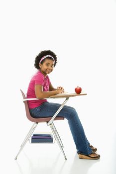 Side view of African American girl sitting in school desk smiling at viewer.