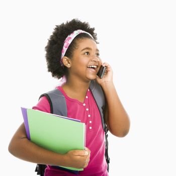 African American girl with books and wearing backpack talking on cell phone.