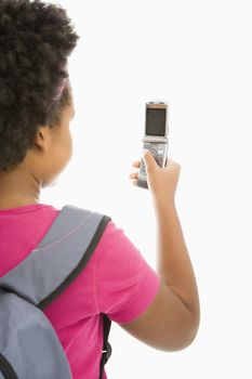 Back view of African American girl with backpack looking at cell phone.