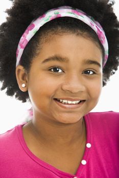 African American girl wearing headband smiling at viewer.