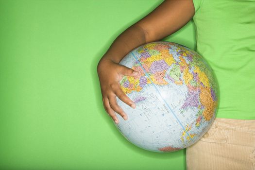 Arm of African American girl holding globe at hip.