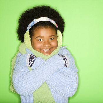African American girl in winter clothing with arms crossed smiling at viewer.