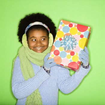 African American girl in winter clothing holding wrapped package.