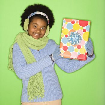 African American girl in winter clothing holding wrapped package.
