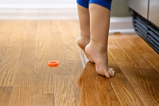 Feet of Caucasian toddler boy with magnets in front of refrigerator.