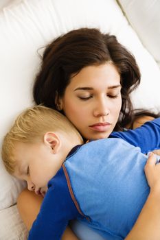 Caucasian mid adult woman with toddler son sleeping in bed.