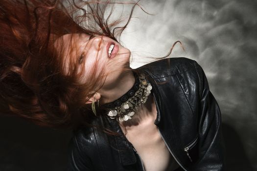 Partially nude Caucasian woman in leather jacket with long hair blowing.