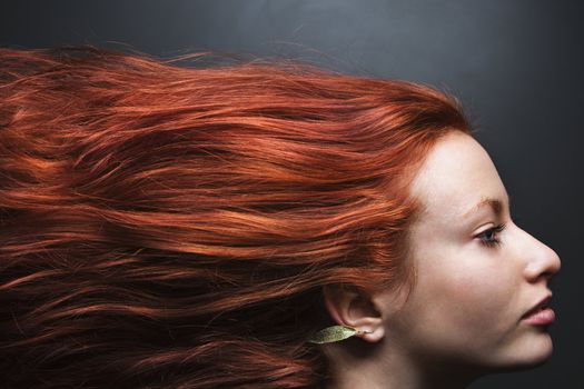 Pretty redhead young woman profile with hair streaming out behind her.