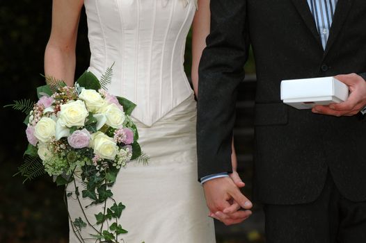 Wedding couple are holding a bouquet and a gift.