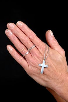 Woman is praying holding her cross. On black clean background.
