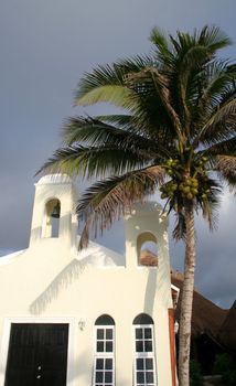 A tropical chapel with a palm tree beside it.