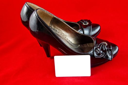 black female shoes with white card on red background 