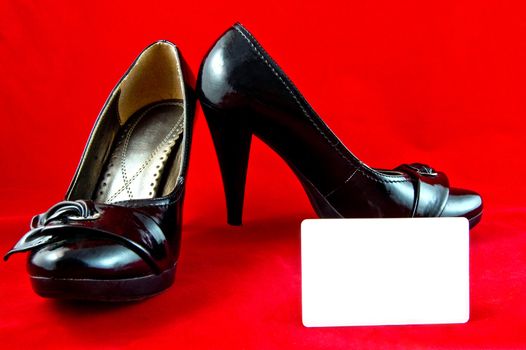 black female shoes with white card on red background 