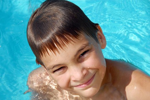 happy teen boy in blue swimming pool portrait