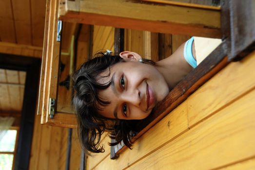 teen girl in wooden house looking trough the window and smiling