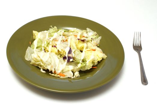 A plate full of fresh salad with dressing on top.