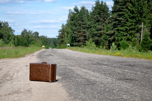 One old suitcase left on a dirt road