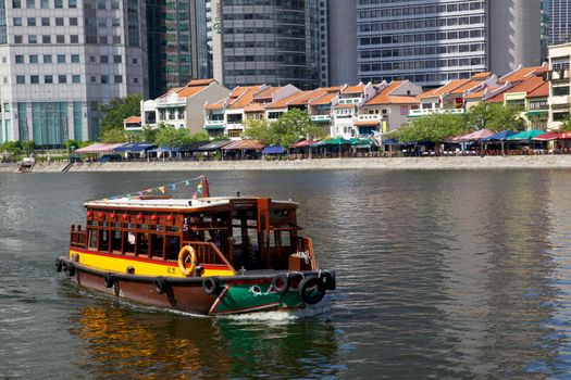 A tourist bumboat motors past Boat Quay on the Singapore River.
