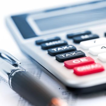 Calculating numbers for income tax return with pen and calculator
