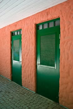 A pair of green doors on a pink plaster wall