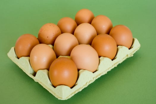 Dozen hen eggs in box in isolated over green