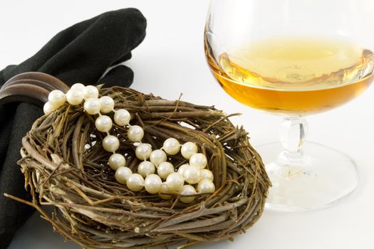 A feminine nest egg of pearls presented with a glass of brandy