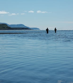 Two people fishing with rods in the sea