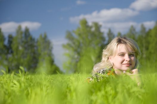 Beautiful young woman lying on green field