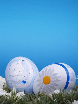 handpainted easter eggs, artificial grass and blossoms, shades of blue background