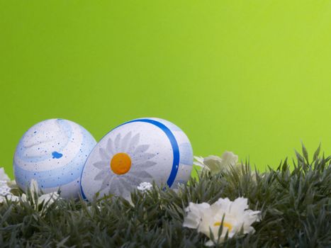 handpainted easter eggs, artificial grass and blossoms, green background