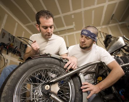Two men working on a chopper-style motorcycle