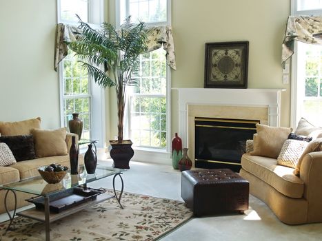 A well decorated family room in a modern american home with an overstuffed sofa, chair and glass coffee table. Large windows make the room very bright and airy.