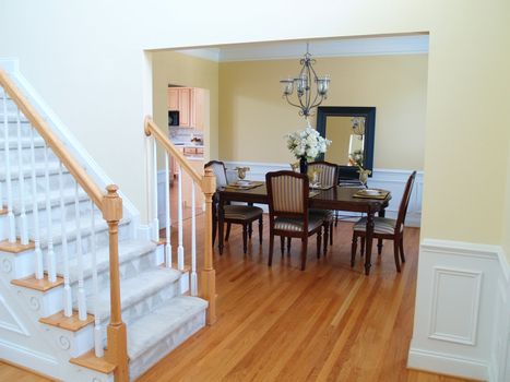 A well staged dining room viewed from the foyer with the staircase in the foreground