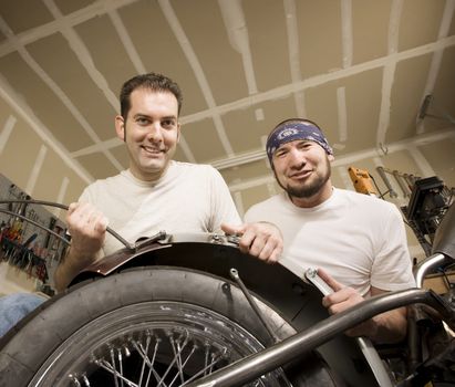 Two men working on a chopper-style motorcycle
