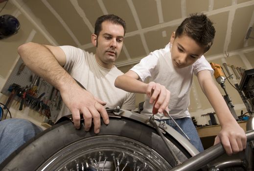 Father and son working on motorcycle in garage