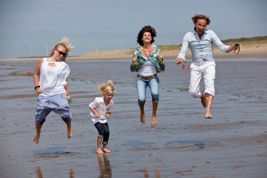 Happy young family at the beach jumping