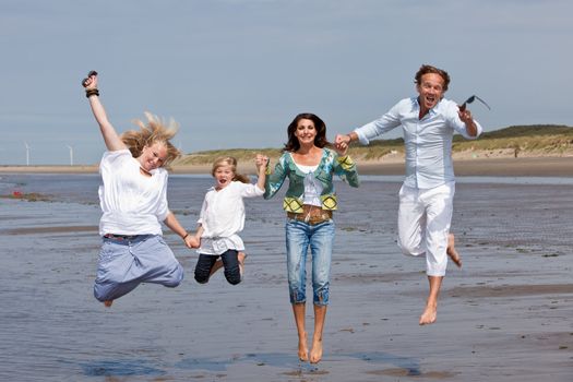 Happy family with two kids jumping in the air on the beach