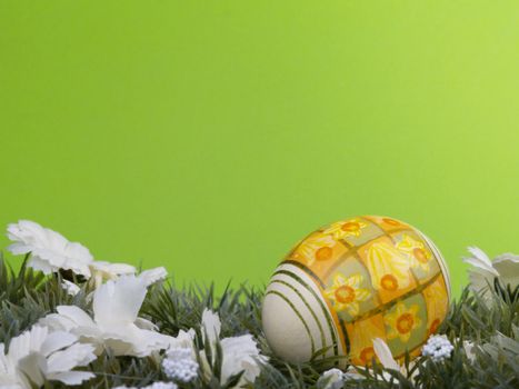 handpainted daffodil design on easter egg, artificial grass and blossoms, green background
