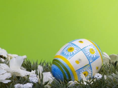 handpainted daisy design on easter egg, artificial grass and blossoms, green background