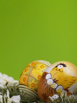 handpainted easter eggs, artificial grass and blossoms, green background