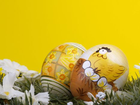handpainted easter eggs, artificial grass and blossoms, yellow background