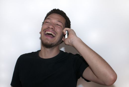 Casual young man laughing on the phone on isolated background