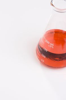 An erlenmeyer flask with red liquid on a white background. Add your text to the background.