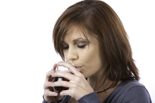 A beautiful young woman drinking a red soda drink from a glass